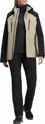 Frau in einer beigefarbenen Jacke mit schwarzen Ärmeln und schwarzen Hosen mit rosa Schuhen. Frau in einer beigefarbenen Jacke mit schwarzen Ärmeln und schwarzen Hosen mit rosa Schuhen.