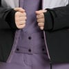 Detail von Händen und Jacke in Lila und Schwarz mit Reißverschlussdetails.