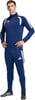 Ein Mann im dunkelblauen Adidas Trainingsanzug mit weißen Streifen und Logo.