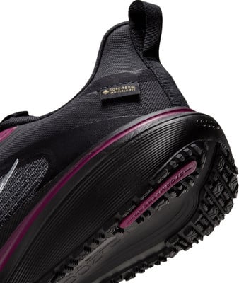 Detail eines schwarzen Schuhs mit violettem Streifen und GORE-TEX-Logo. Detail eines schwarzen Schuhs mit violettem Streifen und GORE-TEX-Logo.
