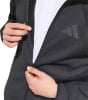 Ein Mann öffnet eine schwarze Jacke mit Adidas-Logo auf der Brust.