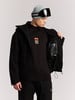 Ein Mann in einer Skijacke und Mütze mit Brille öffnet seine Jacke.