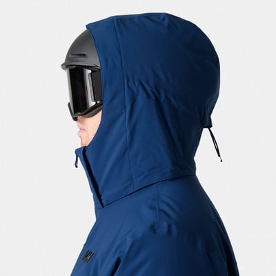 Ein Mann mit Skiausrüstung trägt eine dunkelblaue Kapuzenjacke. Ein Mann mit Skiausrüstung trägt eine dunkelblaue Kapuzenjacke.