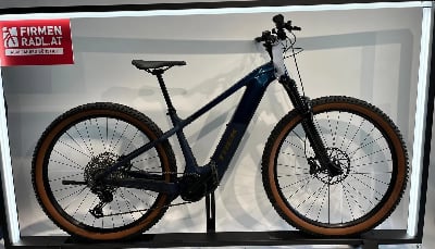 Dunkelblaues Trek E-Bike mit braunen Reifen auf einem Ständer.