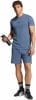 Ein Mann in blauem T-Shirt und Shorts hält eine Wasserflasche.