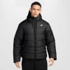 Ein Mann in einer schwarzen Nike-Daunenjacke mit Kapuze und Logo auf der Brust.