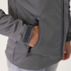Hand in der Tasche einer grauen Jacke mit verstellbarem Klettverschluss am Ärmel.