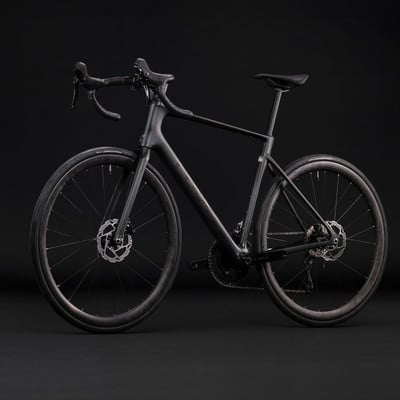 Schwarzes Carbon-Rennrad mit Scheibenbremsen vor schwarzem Hintergrund. Schwarzes Carbon-Rennrad mit Scheibenbremsen vor schwarzem Hintergrund.
