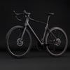 Schwarzes Carbon-Rennrad mit Scheibenbremsen vor schwarzem Hintergrund.