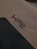 Braunes Logo auf braunem Stoff mit schwarzem Einsatz.