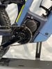 Detail eines modernen Elektrofahrrads mit Kette und Kurbeln im Vordergrund.
