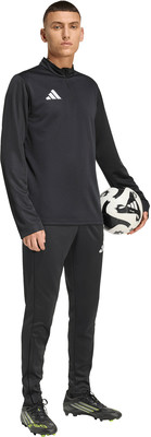 Ein Mann in schwarzer Kleidung hält einen Fußball und trägt Fußballschuhe. Ein Mann in schwarzer Kleidung hält einen Fußball und trägt Fußballschuhe.