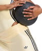 Eine Frau hält einen schwarzen Medizinball in einem gelben Sportoutfit.