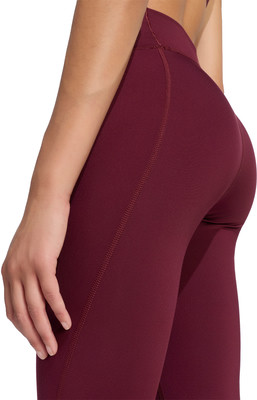 Detail einer Hand und eines Teils der Beine einer Frau in weinroten Leggings. Detail einer Hand und eines Teils der Beine einer Frau in weinroten Leggings.
