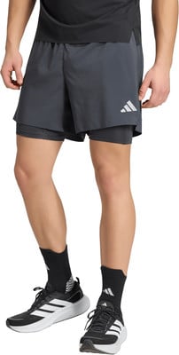 Ein Mann in dunklen Shorts mit Innenslip und schwarzen Adidas-Turnschuhen. Ein Mann in dunklen Shorts mit Innenslip und schwarzen Adidas-Turnschuhen.