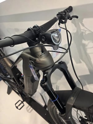 Vorderseite eines schwarzen E-Bikes mit Federung und Licht. Vorderseite eines schwarzen E-Bikes mit Federung und Licht.