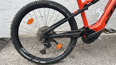 Hinterrad eines orangefarbenen E-Bikes mit Federung und Schaltwerk. Hinterrad eines orangefarbenen E-Bikes mit Federung und Schaltwerk.