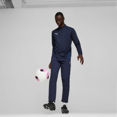 Ein Fußballspieler in dunkelblauer Kleidung dribbelt mit einem rosa-weißen Ball. Ein Fußballspieler in dunkelblauer Kleidung dribbelt mit einem rosa-weißen Ball.