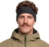 Ein Mann mit Schnurrbart trägt ein dunkles Stirnband und eine Khaki-Jacke.