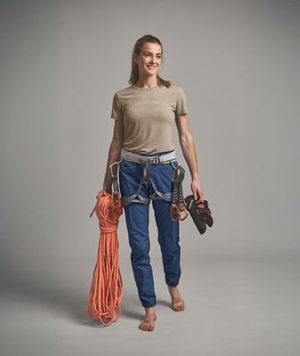 Eine Frau in Kletterausrüstung mit Seil und Schuhen in der Hand. Eine Frau in Kletterausrüstung mit Seil und Schuhen in der Hand.