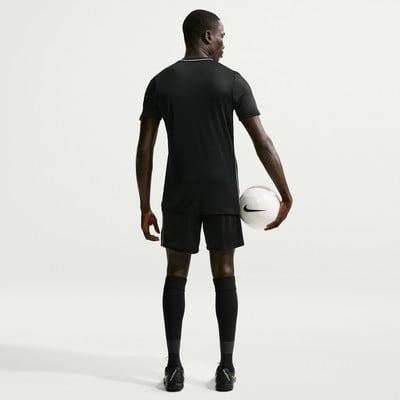 Ein Mann im schwarzen Fußballtrikot und Shorts hält einen Ball. Ein Mann im schwarzen Fußballtrikot und Shorts hält einen Ball.