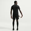 Ein Mann im schwarzen Fußballtrikot und Shorts hält einen Ball.