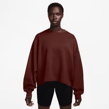 Eine Frau in einem dunkelroten Pullover und schwarzen Shorts steht vor weißem Hintergrund.