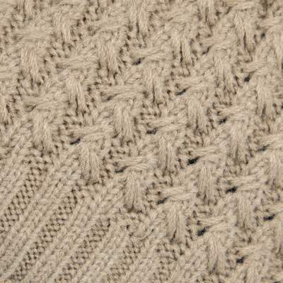 Beiger Strickstoff mit einem feinen Zopf- und Flechtmuster. Beiger Strickstoff mit einem feinen Zopf- und Flechtmuster.