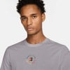 Ein Mann in einem grauen T-Shirt mit dem Nike Court-Logo auf der Brust.