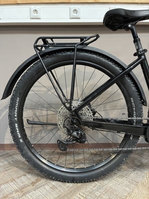 Hinterrad eines schwarzen Fahrrads mit Gepäckträger und Schutzblech.