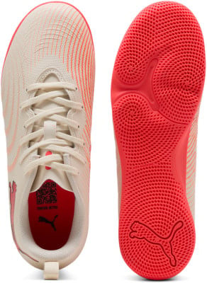 Weiße Puma Hallenfußballschuhe mit orangefarbenem Streifenmuster und roter Sohle. Weiße Puma Hallenfußballschuhe mit orangefarbenem Streifenmuster und roter Sohle.