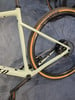 Ein grünes Fahrrad mit schwarzen Punkten und einem orangen Streifen am Reifen.