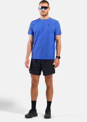 Ein Mann in einem blauen T-Shirt und schwarzer Hose steht mit den Armen am Körper.