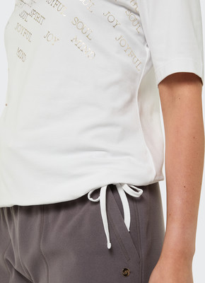 Damen-T-Shirt mit goldfarbenem Aufdruck und grauer Jogginghose. Damen-T-Shirt mit goldfarbenem Aufdruck und grauer Jogginghose.