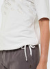 Damen-T-Shirt mit goldfarbenem Aufdruck und grauer Jogginghose.