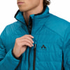 Ein Mann schließt eine blaue McKinley-Daunenjacke mit Logo auf der Brust.