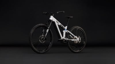Ein weißes E-Bike mit Federung vor schwarzem Hintergrund.