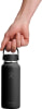 Eine Hand hält eine schwarze Hydro Flask Flasche am Henkel.