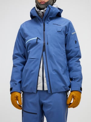 Ein Mann in einer blauen Skijacke mit Kapuze und gelben Handschuhen. Ein Mann in einer blauen Skijacke mit Kapuze und gelben Handschuhen.