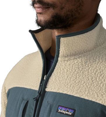 Ein Mann trägt eine beige-blaue Fleecejacke mit Patagonia-Logo. Ein Mann trägt eine beige-blaue Fleecejacke mit Patagonia-Logo.