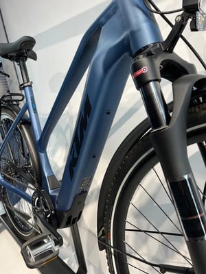 Ein blaues KTM E-Bike mit Federgabel und Schutzblechen.