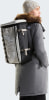 Eine Frau mit einem Rucksack auf dem Rücken in einer grauen Jacke und Mütze.