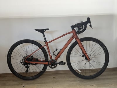 Ein rosafarbenes Fahrrad mit schwarzem Lenker und Sattel steht an der Wand. Ein rosafarbenes Fahrrad mit schwarzem Lenker und Sattel steht an der Wand.