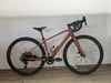 Ein rosafarbenes Fahrrad mit schwarzem Lenker und Sattel steht an der Wand.