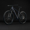 Dunkelblaues Mountainbike mit schwarzen Rädern und Federung auf dunklem Hintergrund.