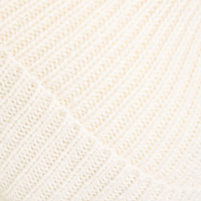 Detail einer cremefarbenen Strickware mit Rippenmuster.
