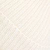 Detail einer cremefarbenen Strickware mit Rippenmuster.