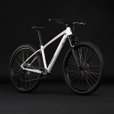 Ein weißes Mountainbike mit schwarzen Rädern und Federung vor schwarzem Hintergrund.