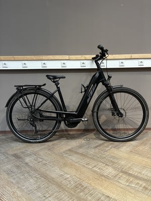 Ein schwarzes KTM E-Bike steht auf einem Holzboden vor einer grauen Wand. Ein schwarzes KTM E-Bike steht auf einem Holzboden vor einer grauen Wand.