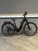 Ein schwarzes KTM E-Bike steht auf einem Holzboden vor einer grauen Wand.